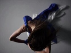 portrait of woman draped in blue silk fabric as she reaches up to camera Stock Footage