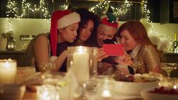 Playful friends in santa hats and reindeer antlers taking selfie at candlelight Christmas table Stock Footage