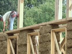 WS ZO Carpenter hammering around bales of straw during framing of an energy efficient post / Grass Lake, Michigan, USA  Stock Footage