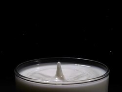 CU SLO MO Shot of Drop falling into glass of milk against black background / Calvados, Normandy, france Stock Footage