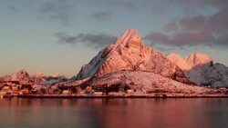 Wispy clouds flow over a snow-dusted mountain at sunset. Stock Footage