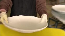 An artist buffs the bottom of a petal shaped serving platter. Stock Footage