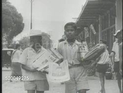 1945: INDONESIA NATIONAL REVOLUTION: VS Indonesian people reading chart on board, children handing out flyers, nationalists parading w/ signs, male saluting. WS Sign w/ writing on wall, '...Government ... by the people.' Dutch Empire Instructional Video
