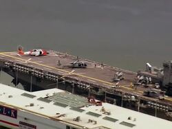 Aerial zoom out helicopter on deck of Iwo Jima aircraft carrier moored at River Walk mall / New Orleans, Louisiana Stock Footage