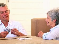 Senior couple sitting on floor playing cards Stock Footage