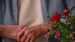 An older woman rubs her stiff, arthritic hands after touching the buds on a potted plant. Stock Footage