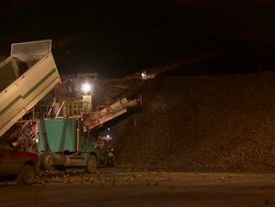 Slow zoom into the moving conveyor belt that's dropping the sugar beets into large piles at the back of the warehouse. Stock Footage