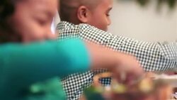 Grandfather passes dish to grandson while cute young girl serves herself spoonful of salad Stock Footage