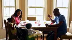 MS Smiling family sitting together at dining room table eating breakfast Stock Footage