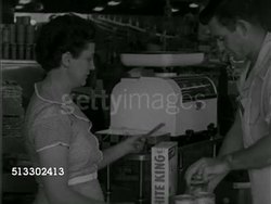 1952: LAS VEGAS, NEVADA: GROCERY STORE: Angled MS Woman at check out counter w/ male ringing up purchase on manual cash register, handing woman her change, bagging groceries in paper bag, woman picking up groceries.   Shopping, female, housewife. Instructional Video