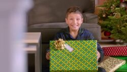 Excited young boy shakes Christmas present for camera Stock Footage