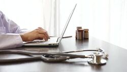 Young Woman doctor browsing pages on laptop, typing letter, consulting patients Stock Footage