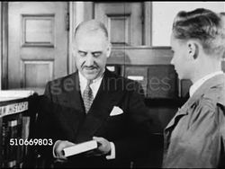 1949: DRAMATIZATION: Suited male continuing to help choose topic for teen, suggesting 1920s, handing teenager a book, he thanks him.  Public library. Instructional Video