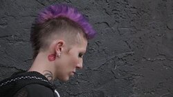 Profile portrait cool young woman with purple mohawk and lip tattoo on neck Stock Footage