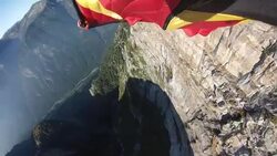 POV from wingsuit jumpers foot as he flies near a cliff face Stock Footage