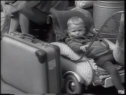 B/W 1961 small boy lying in stroller by luggage outdoors / East German refugees - Berlin Wall Stock Footage