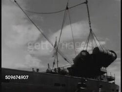 1941: FRENCH TERRITORIES: NEW CALEDONIA: WS Unloading steel drums by crane from ship, Indigenous Melanesian men rolling drums. US Soldiers at attention, officer passing, soldiers shouldering rifles. MS US Soldiers standing at attention. WWII Instructional Video