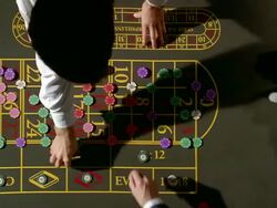 High angle pan croupier and gambler placing chips on roulette table / croupier spinning roulette wheel Stock Footage