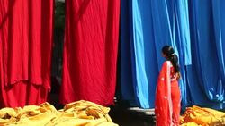 A woman checks the quality of freshly dyed fabrics in a sari garment factory. Stock Footage