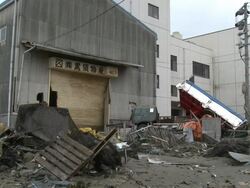 Destruction caused by tsunami after magnitude 9 Tohoku earthquake, north east Japan, March 2011. Truck and debris lies smashed against industrial building Stock Footage