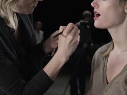 MS TD TU PAN Female fashion model backstage at fashion show make-up artist applying make-up Stock Footage