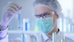 Scientist, doctor, student, in clean suit examining sample in test tube Stock Footage