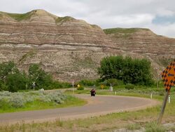 A motorcyclist passes on the road near the rock formations of Badlands Stock Footage