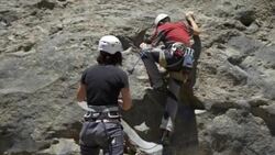 A woman belaying a man while rock climbing. Stock Footage