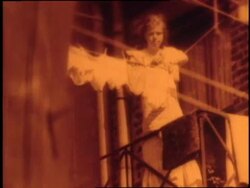 A woman hangs laundry on a clothesline from a fire escape on a tenement building. News Clip