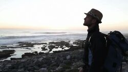 Solo Traveler on rocky coastline at sunset Stock Footage