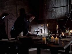 Nostradamus sits at a desk lit by candles and begins reading a book. Stock Footage