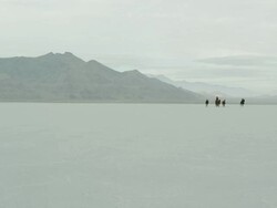 Horses running with cowboys riding across salt flats. Stock Footage