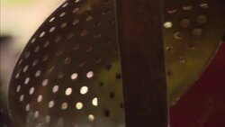 Hands pull silk threads as a slotted spoon scoops silk cocoons out of a kettle. Stock Footage