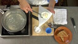 Overhead removing a freshly poached egg from a boiling pan of water and placing on a plate with breakfast toast. Stock Footage