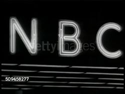 1937: THEATRE DISTRICT: NEW YORK: NIGHT: WS CBS Radio Theatre. NBC Neon sign. Broadcast studio clock 'on the air' sign lighting up. Comedian Jack Benny (1894-1974) holding script, laughing behind NBC mic, Laughing audience, Jack Benny w/ writers. Instructional Video