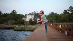 Young boys on dock hoist crab-trap and throw it into the river Stock Footage