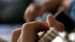 Young man playing a black acoustic guitar Stock Footage