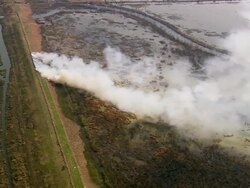 Aerial brush fire on train track / smoke billowing over marshy landscape / Louisiana Stock Footage