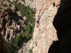Handheld shot of rock-climber slowly maneuvering up a vertical formation. Stock Footage