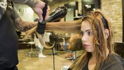 Male Hair stylist drying a female clients hair Stock Footage