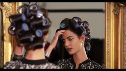 A woman with hair in rollers, looks in a mirror Stock Footage