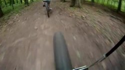 The front wheel of a bicycle follows another cyclist down a dirt path. Stock Footage
