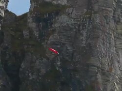 Wing suit flier jumps from cliff soars above valley below Stock Footage
