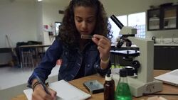 Schoolgirl using microscope in science laboratory classroom Stock Footage