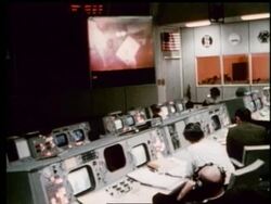 high angle of men at controls watching astronauts on screen Stock Footage