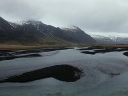WS View of Thaw water flow goes down rivers and behind snow covered mountain / Iceland  Stock Footage