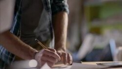Man at workbench takes notes on graph paper Stock Footage