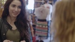 Young woman brings cowboy boots to checkout counter and hands credit card to cashier who swipes on tablet computer Stock Footage