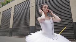 Cool young ballerina dancing listening to music with headphones and mp3 player in urban alley Stock Footage