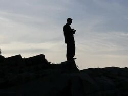 WS Man standing on rocks typing on mobile phone / Portland, ME, United States Stock Footage